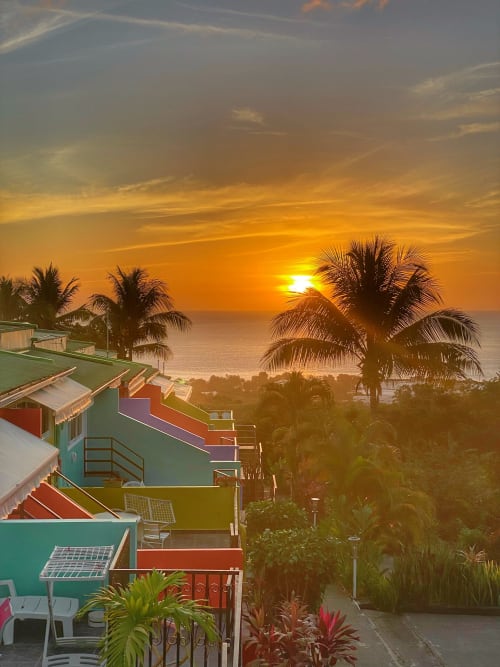 Coucher de soleil sur l'océan tropical de l'hôtel Paradis Tropical à Baillif, Guadeloupe, avec ses bâtiments colorés en bord de plage et palmiers