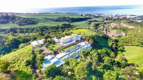 Vue aérienne de l'hôtel Paradis Tropical niché dans les collines verdoyantes de Bailiif, Guadeloupe, avec piscines et horizon océanique