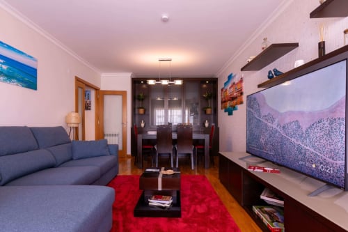Modern OceanBreeze apartment in Matosinhos with blue sofa, red rug, dark dining area, and flat-screen TV
