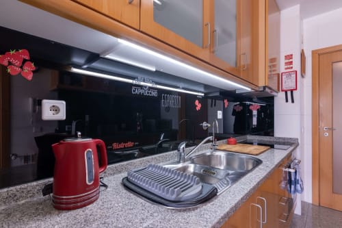 Modern kitchen in OceanBreeze apartment at EcoHost Matosinhos with red kettle, stainless steel sink, and black backsplash