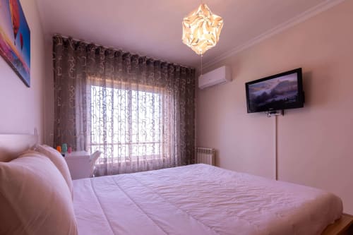 Pink bedroom with double bed, TV, patterned curtains, and balcony at OceanBreeze apartment in Matosinhos