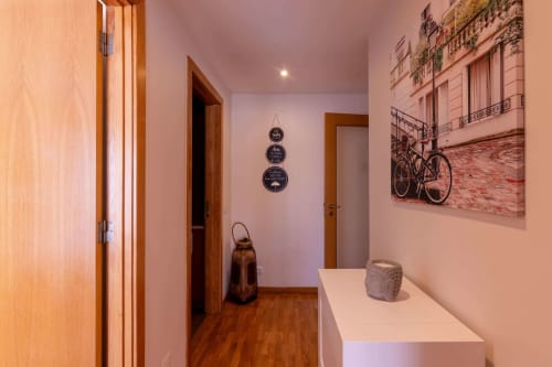 Modern hallway at EcoHost in Matosinhos with wooden doors, pink walls, bicycle artwork, and decorative elements