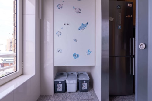 Kitchen nook with three recycling bins and sea-themed wall decals in EcoHost Praia apartment, Matosinhos