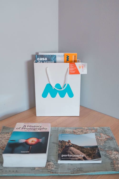White shopping bag with turquoise wave logo displaying books and magazines in Matosinhos apartment