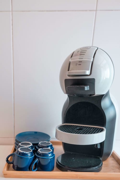 Delonghi coffee maker with blue cups on wooden tray in EcoHost apartment kitchen, Matosinhos