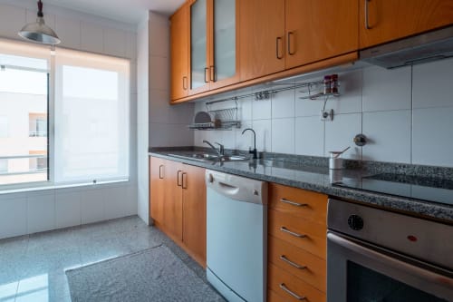 Modern kitchen with wooden cabinets, granite countertop, stainless steel appliances, and white subway tile backsplash at