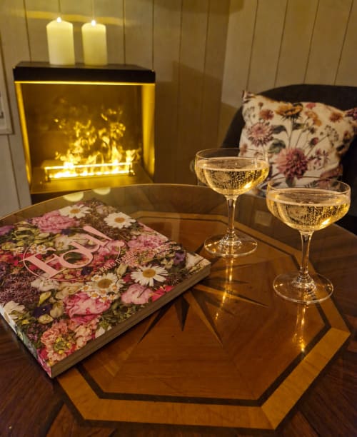 Ambiance romantique à Casa Pertica : verres de champagne, livre fleuri et foyer chaleureux à Ceton.