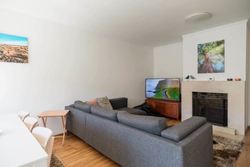 Modern living room with gray sofa, fireplace, TV, and nature artwork at EcoHost Gaia Beach&Golf apartment in Arcozelo
