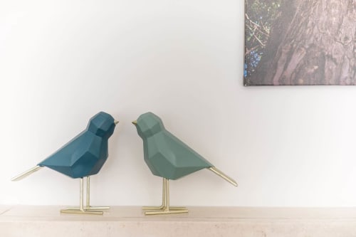 Two geometric bird sculptures in teal and green with brass legs on shelf at EcoHost Arcozelo, Portugal eco-friendly