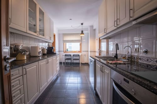 Modern galley kitchen with cream cabinets, dark countertops, stainless steel appliances, and tile flooring at Gaia Beach&Golf