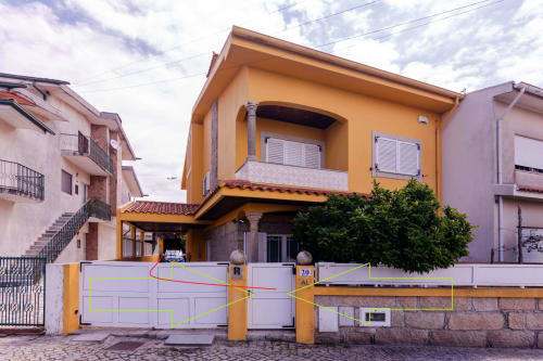 Yellow contemporary house in Perafita with white gate, garden view entrance for EcoHost apartment rental near airport
