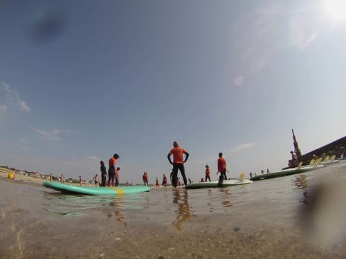 Surf lesson at Matosinhos beach with instructors and participants in wetsuits on surfboards