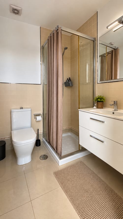 Modern bathroom in Banama Coliving hostel, Corralejo with shower enclosure, white vanity, and toilet