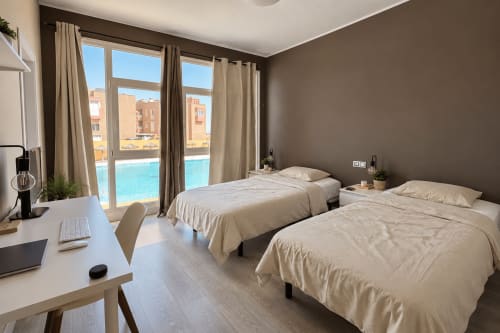 Premium shared room at Banama Coliving hostel in Corralejo with twin beds, pool view, and work desk