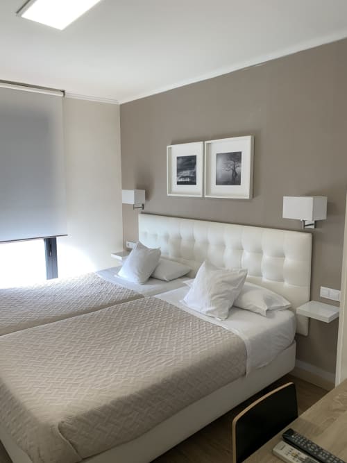 Moderno dormitorio doble en Hostal El Rocío Madrid con cabecero capitonado color crema, almohadas blancas, decoración neutra y cuadros enmarcados