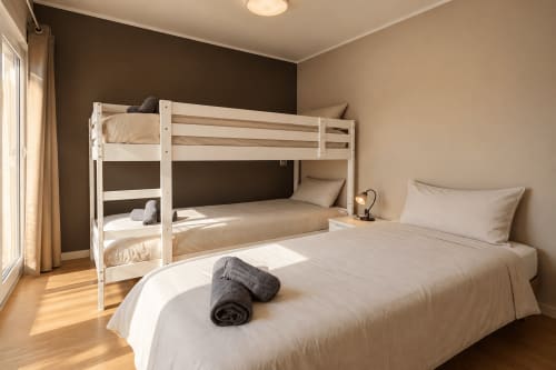 Dorm Canada bedroom at Banama Coliving hostel in Corralejo with bunk beds, queen bed, wooden floors, and balcony access