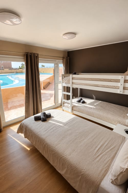 Dorm room at Banama Coliving hostel in Corralejo with bunk beds, single bed, pool view balcony