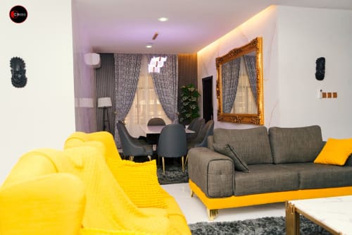 Modern apartment living room at OD Cribs Abuja with yellow and gray sofas, dining area, and contemporary decor