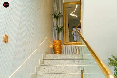 Modern staircase at OD Cribs Abuja with marble steps, gold handrail, and elegant mirror decor