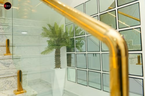 Modern bathroom at OD Cribs Abuja with glass shower enclosure, palm plant, and brass fixtures