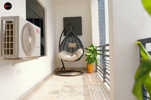 Modern balcony at OD Cribs Abuja with hanging chair, potted plant, AC unit, and contemporary décor