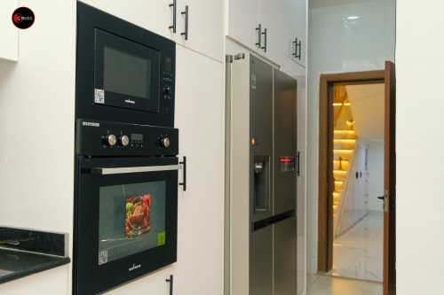 Modern black built-in oven and microwave with stainless steel refrigerator in OD Cribs CASA apartment kitchen, Abuja