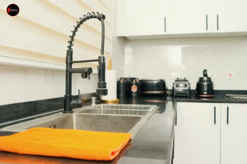 Modern kitchen in CASA OD apartment at OD Cribs Abuja with black faucet, stainless sink, and white cabinetry