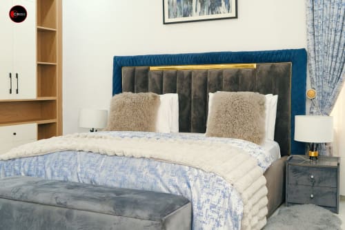 Modern bedroom at OD Cribs Abuja with blue upholstered headboard, neutral bedding, and contemporary furnishings