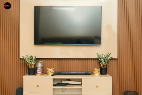 Modern TV entertainment setup at OD Cribs Abuja with wall-mounted flat screen, soundbar, potted plants, and cream cabinet in