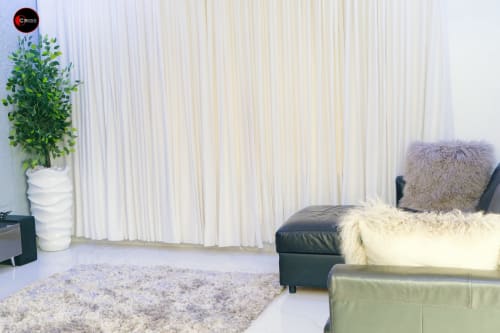 CASA OD apartment sitting area at OD Cribs Abuja featuring leather sofa, white curtains, potted plant, and textured rug