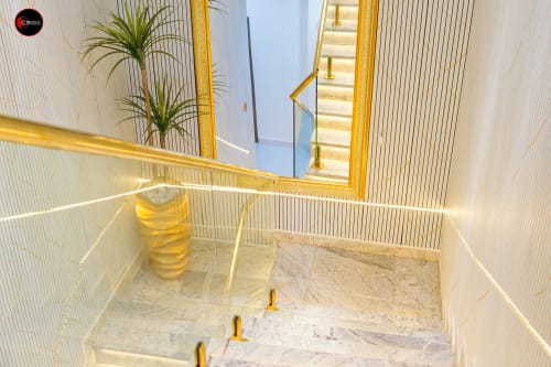 Modern staircase with gold railings and marble steps at OD Cribs CASA apartment in Abuja, featuring potted plant and mirror