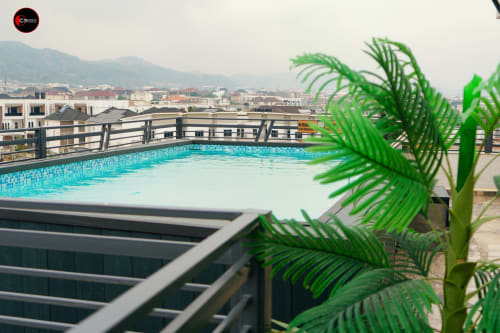 OD Cribs rooftop pool with city views, balcony railing, and tropical plants in Abuja