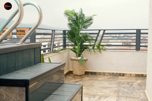 OD Cribs CASA apartment balcony in Abuja with potted palm plant, seating area, and city view over railing