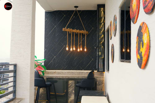 OD Cribs CASA apartment dining area in Abuja with black marble wall, brass pendant lights, and colorful circular artwork