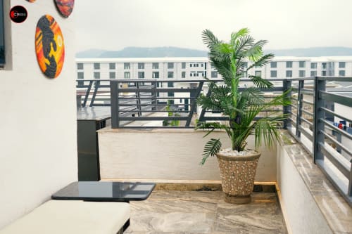 OD Cribs Abuja apartment balcony with palm plant, pool view, and modern railing