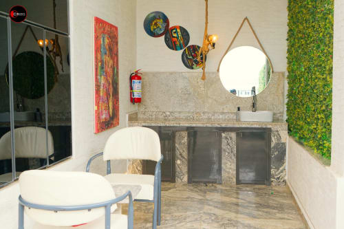 Modern bathroom at OD Cribs CASA apartment in Abuja with round mirror, vanity sink, decorative wall art, and green living