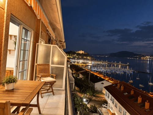 Terraza del apartamento Holibai en Baiona con vistas al mar, marina iluminada y costa al atardecer