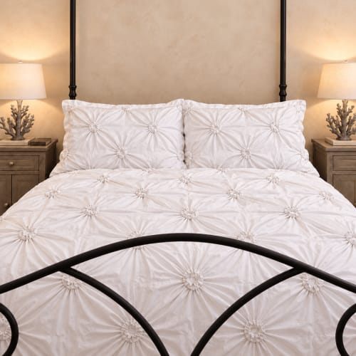Elegante biancheria bianca arricciata su letto con struttura in metallo nero, comodini con lampade e decorazioni presso B&B I Mori, Catania