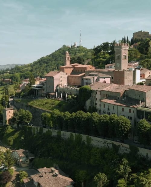 Paesaggio medievale di Forlì con tetti in terracotta, torri in pietra e dolci colline verdi attorno a Corte Livia B&B