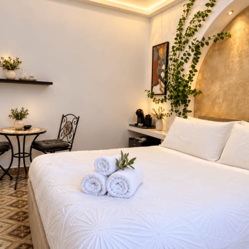 Quarto Kalsa na B&B I Mori Catania: quarto moderno com roupa de cama branca, toalhas enroladas, decoração de hera verde e detalhes em dourado