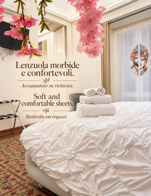 Elegancka sypialnia w B&B I Mori Catania z białą pościelą, różowymi kwiatami i włoskim tekstem na ścianie