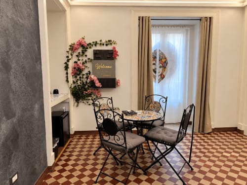 Elegancki pokój B&B w Katanii z meblami z kutego żelaza, florystyczną dekoracją ściennej i podłogą z płytek w kratkę obok drzwi francuskich