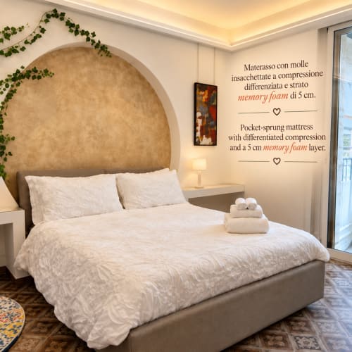 Quarto elegante no B&B I Mori em Catania com grande cabeceira arqueada, roupa de cama branca e colchão de espuma viscoelástica