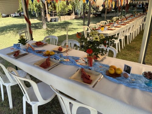Outdoor garden banquet setup at Les Jardins Du Soleil in Avignon with decorated tables, blue runners, flowers, and white