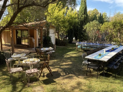 Garden patio at Les Jardins Du Soleil B&B in Avignon with dining tables, chairs, and swimming pool surrounded by trees