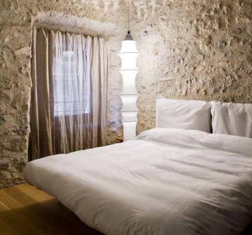 Rustic stone bedroom at Alemanys 5 B&B in Girona with white bedding and pendant lighting