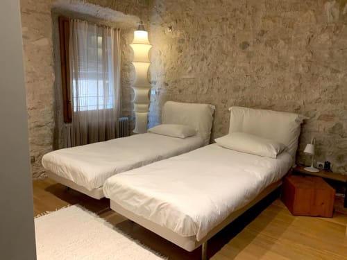 Twin bedroom at Alemanys 5 B&B Girona with cream bedding, stone walls, and modern lamp