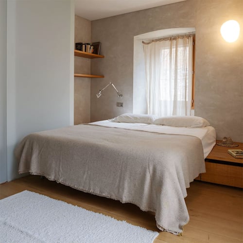 Minimalist bedroom at Alemanys 5 B&B in Girona with bed, wooden shelves, and glass doors overlooking nature