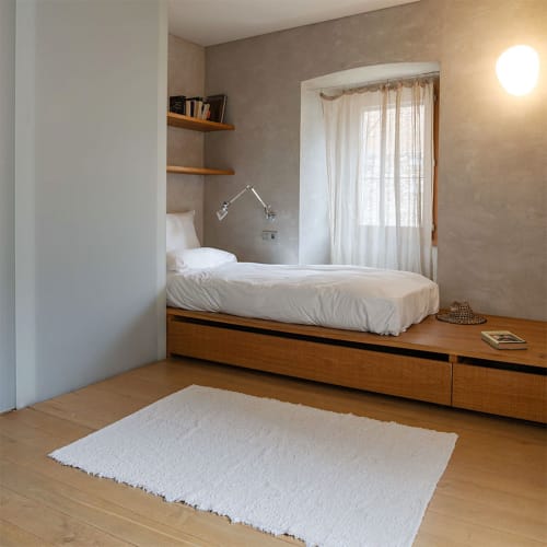 Modern bedroom at Alemanys 5 B&B Girona with wooden platform bed, white bedding, and large window