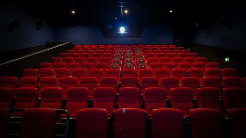 Salle de cinéma vide aux sièges rouges et éclairage bleu, expérience cinématographique à l'auberge Yasi à Lyon